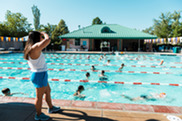 A lifeguard stands in front of swimmers at a pool