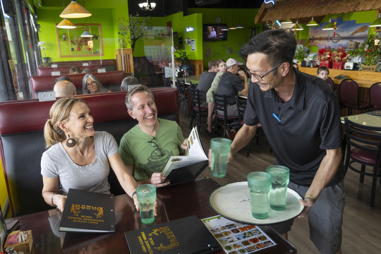 Two people getting water at a restaurant. 
