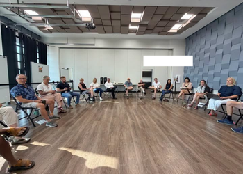 A crowd sits in a circle for First Fridays Coffee at the Superior Civic Space