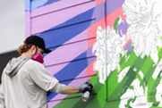 Artist Andrew Norris spray paints a colorful mural ahead of the Superior Mural Festival