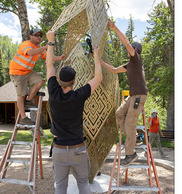 HYBYCOZO installation with three people placing the final piece on a complex metal art installation