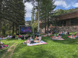 People on lawn viewing large movie screen 