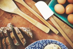 Eggs, Bread, Spatula and Wooden Spoons spread out on wood block