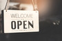A sign hanging saying, "we are open."