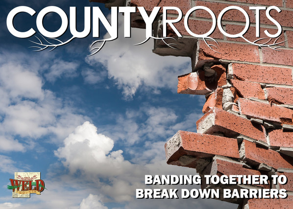 A brick wall with a portion of it broken down and the sun shining through. Text reads "Banding together to break down barriers."