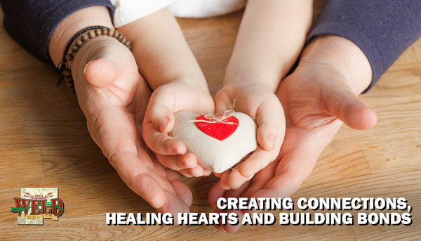 A child's hands and adult hands holding a heart ornament. Text reads: "Creating connections, healing hearts and building bonds."