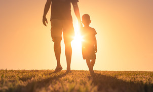 A parent and child walking in the glow of the sunlight. 