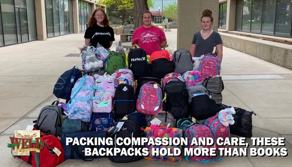 Members of the Youth Executive Council standing by backpacks. Text reads: "Packing compassion and care, these backpacks hold more than books."