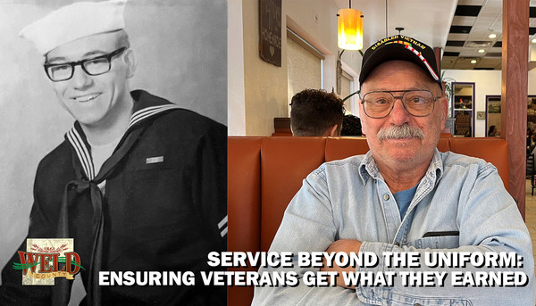 A man in his Navy Uniform and sitting in a restaurant booth with his arms folded. 
