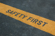 A stripe in pavement with the words "safety first written on them." 