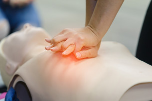 Hands performing CPR on a dummy.