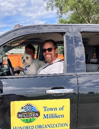 Town of Milliken branded truck, during Milliken's Beef and Bean Parade, with a man and a white dog inside