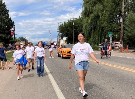 Foster Care in Weld County staff and families walking in Millkien's Beef and Bean Parade