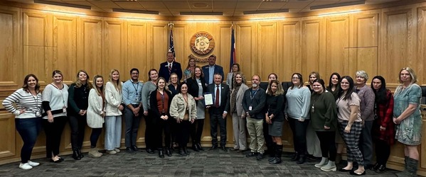 Weld County Adoption Team, posing with the Adoption Month proclamation, with Board of County Commissioners