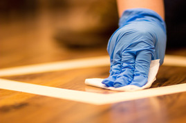 A hand wiping down a wood floor to collect environmental samples.
