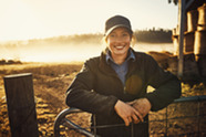 A woman smiling leaning up against a fence. 