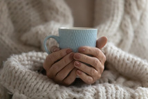 image of woman covered in blanket holding a mug of tea