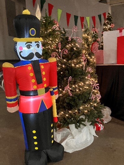 A large inflatable nutcracker beside a decorated Christmas tree with white lights on it