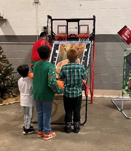 Three young boys playing a basketball arcade game