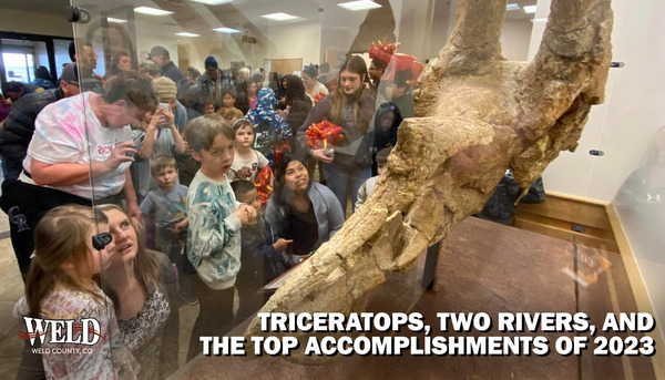People looking at Pops the Triceratops in its display case. Text reads: Triceratops, Two Rivers and the top accomplishments of 2023.