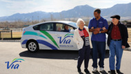 A Via Mobility driver walking with an elderly couple.