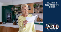 A woman holding a tax bill in her kitchen.