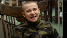 Photo of young boy, James, sitting in a chair and smiling at camera.