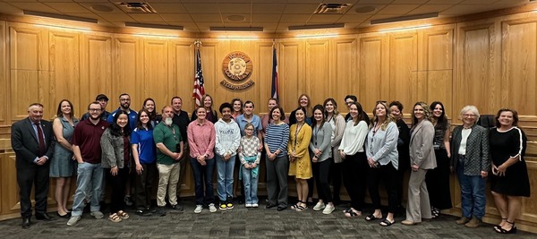 Photo of foster care team at the May 1 board meeting, posing with commissioners.