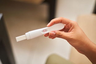 A woman holding a pregnancy test.