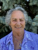 Photo of Jane Hansher, 2024 Hall of Fame Recipient, smiling beside an evergreen tree