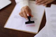 A  Person stamping "approved" on a document.