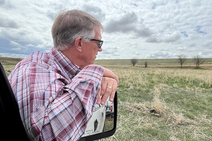 Curtis Hall leaning against a truck, looking ahead.