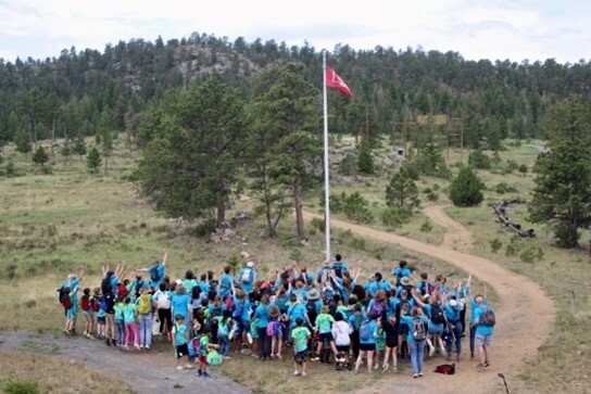 A group of kids raising a red flag on a flagpole