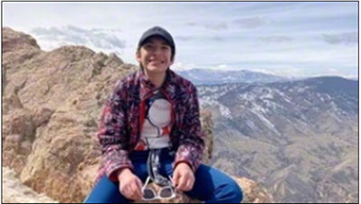 A young boy, Dante, sitting on a rock and smiling