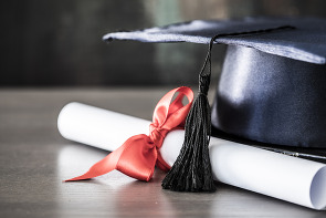 A diploma and graduation hat on a table.