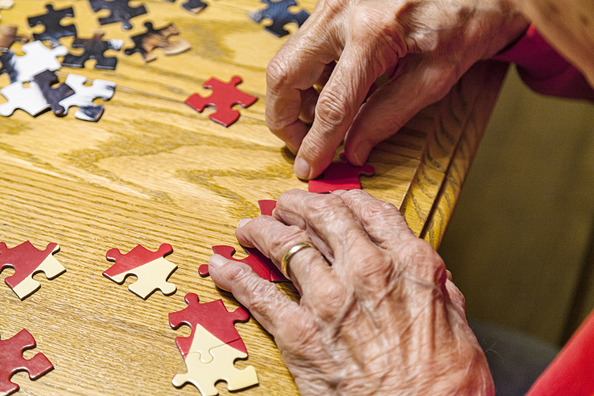 A man's hands putting together a puzzle.