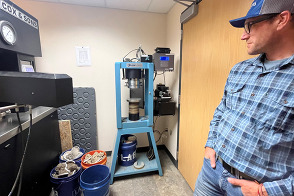 Ryan Axtman, Construction Inspection Supervisor for the Weld County Department of Public Works, looking at a machine in the soils lab. 