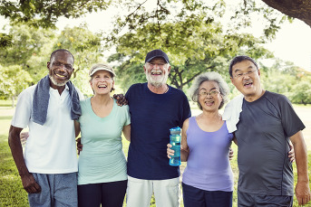 Group of senior adults smiling and laughing. They are wearing workout clothes. 