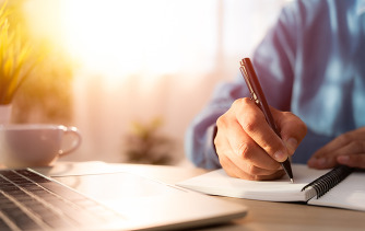Close up of man's hand holding a pen and writing in notebook