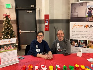 A man and woman sitting at a table for Foster Source filled with small toys.