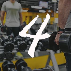young man training with dumbbells in a weight room at the gym