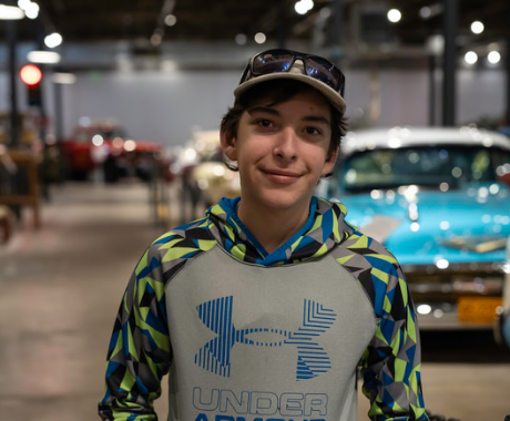 A teenage boy in a ballcap and hoodie smiling. 