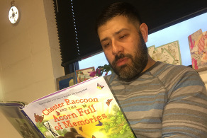 A man, Eric Cano, reading a children's book.