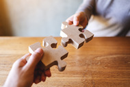 Two puzzle pieces being connected, symbolizing a partnership.