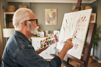 Older man painting on a canvas