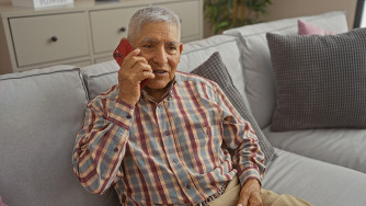 Senior man sitting on couch and talking on cell phone
