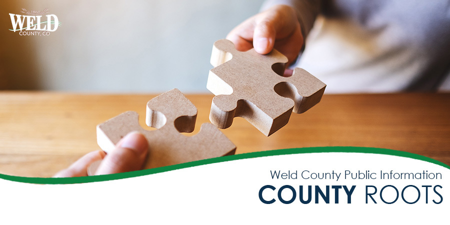 Two people connecting wooden puzzle pieces together.