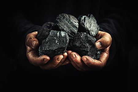 Hands holding a pile of coal.