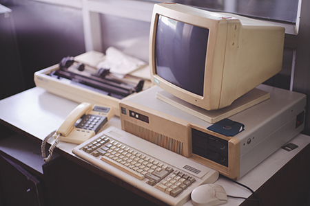 An old computer, monitor and keyboard sitting on a desk next to a dot matrix printer.
