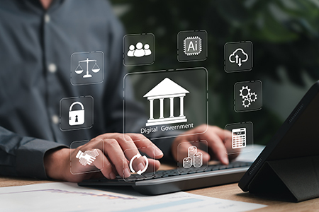 Two hands typing on a laptop keyboard. Various icons float on the picture; one reads digital government.